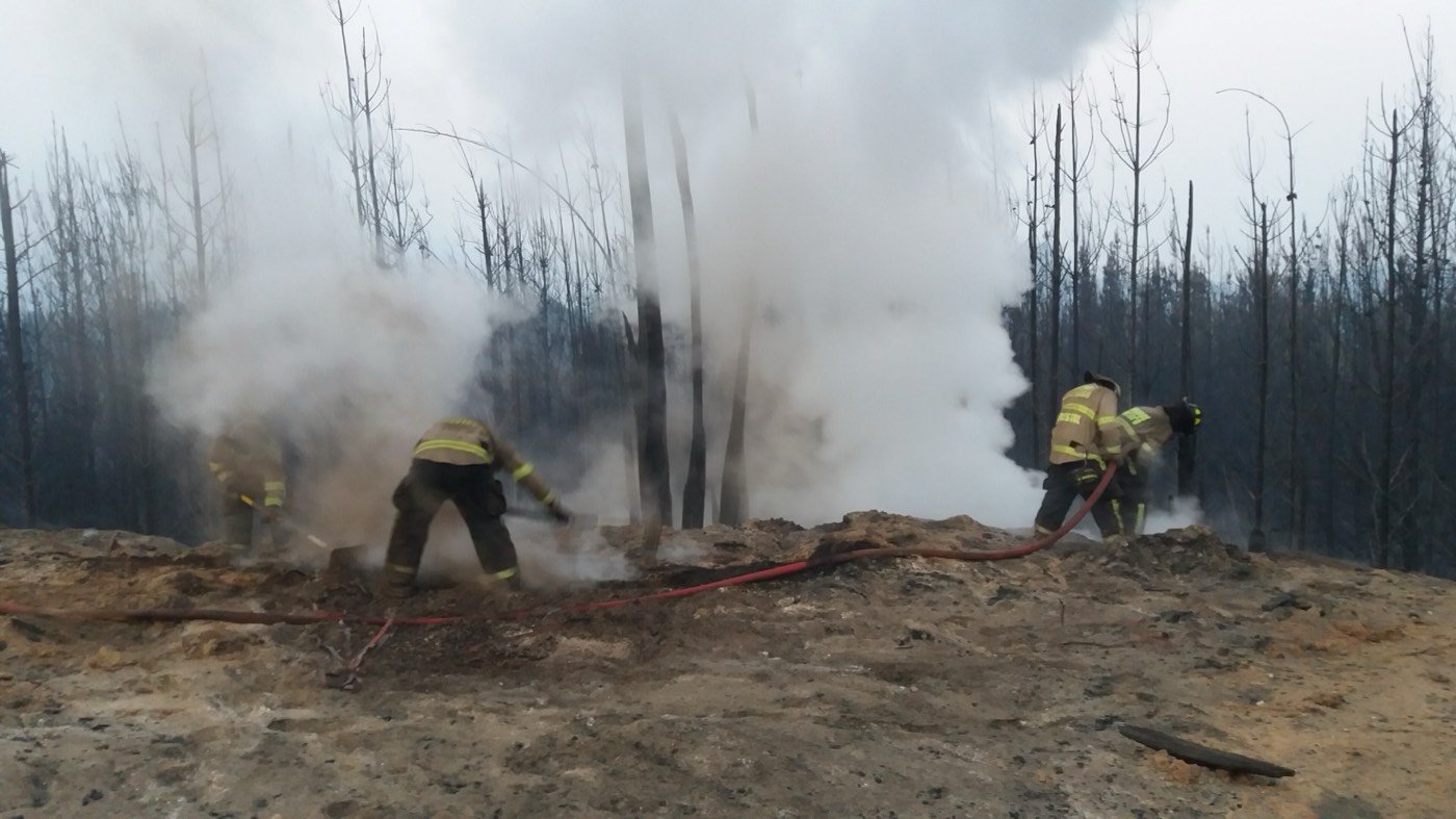 Bomberos combatiendo un incendio forestal entre el humo